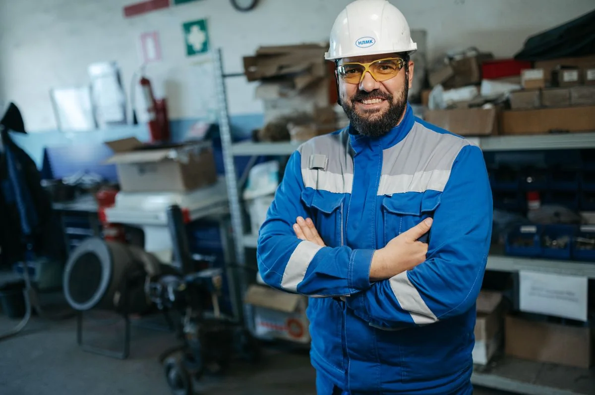 Lächelnder Handwerker in blauer Arbeitskleidung – Symbolfoto